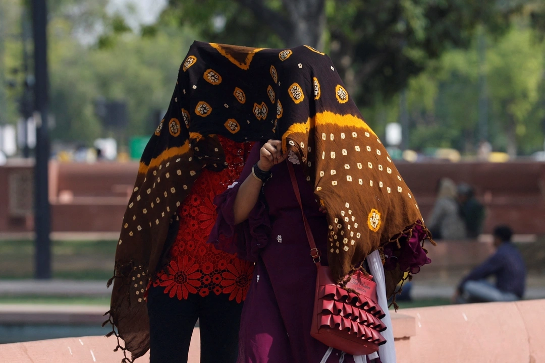 Women take shelter under a cloth, as they walk across a garden on a hot summer day near India Gate, in New Delhi, India May 15, 2023. REUTERS/Anushree Fadnavis/ File photo