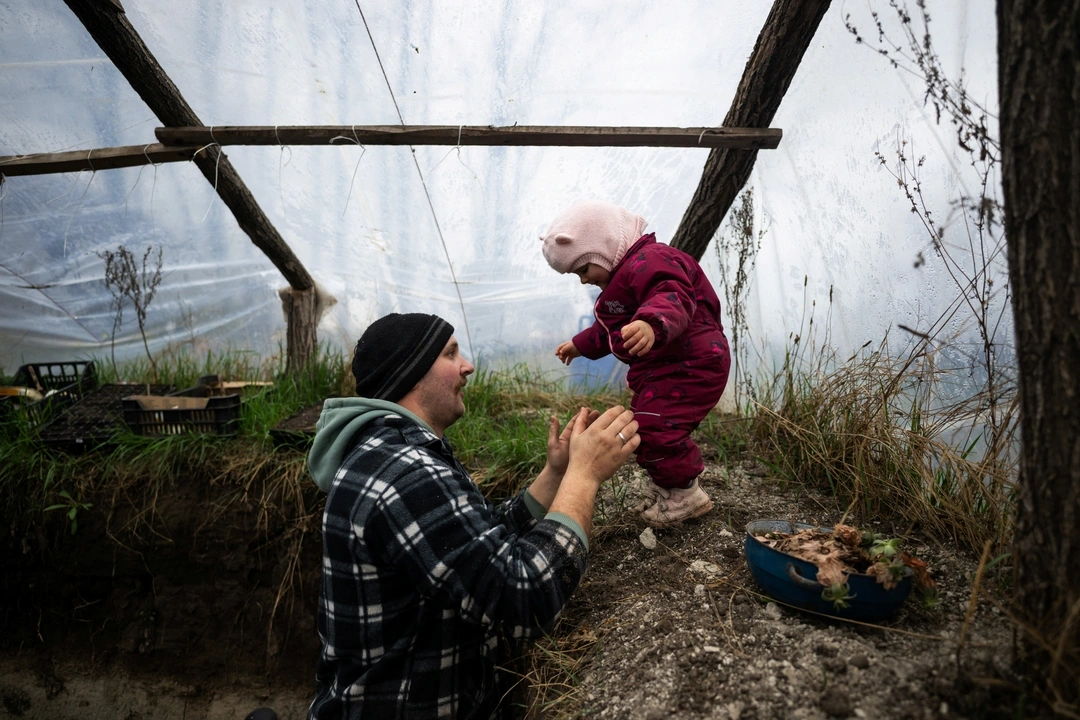 Laszlo Kemencei, 28, plays with his daughter Boroka in the underground greenhouse at their farm near Ladanybene, Hungary, March 7, 2024.  REUTERS/Marton Monus