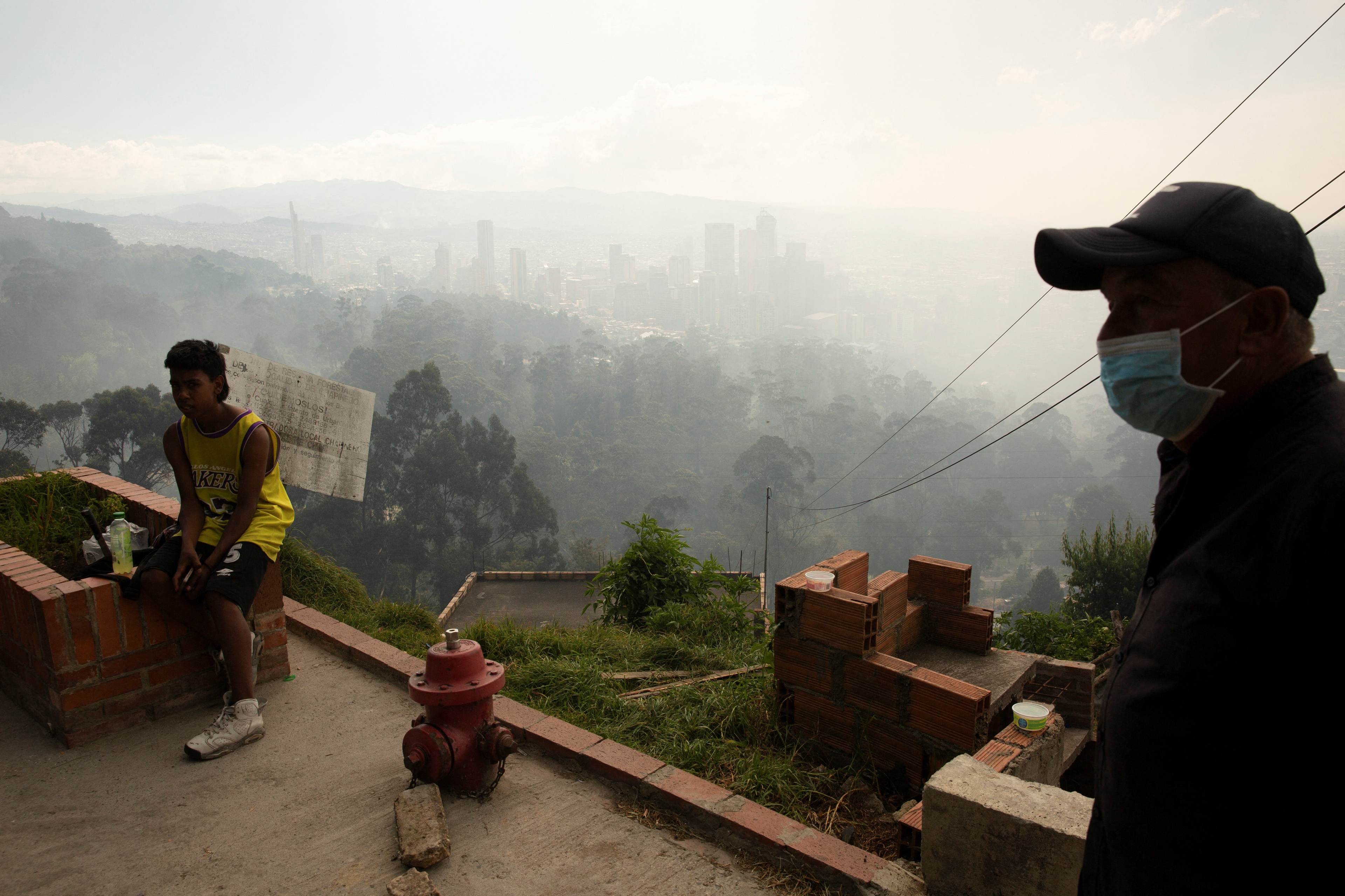 A man wears a face mask after the district government declared an air quality emergency due to forest fires on a hill, in Bogota, Colombia, January 26, 2024. REUTERS/Antonio Cascio