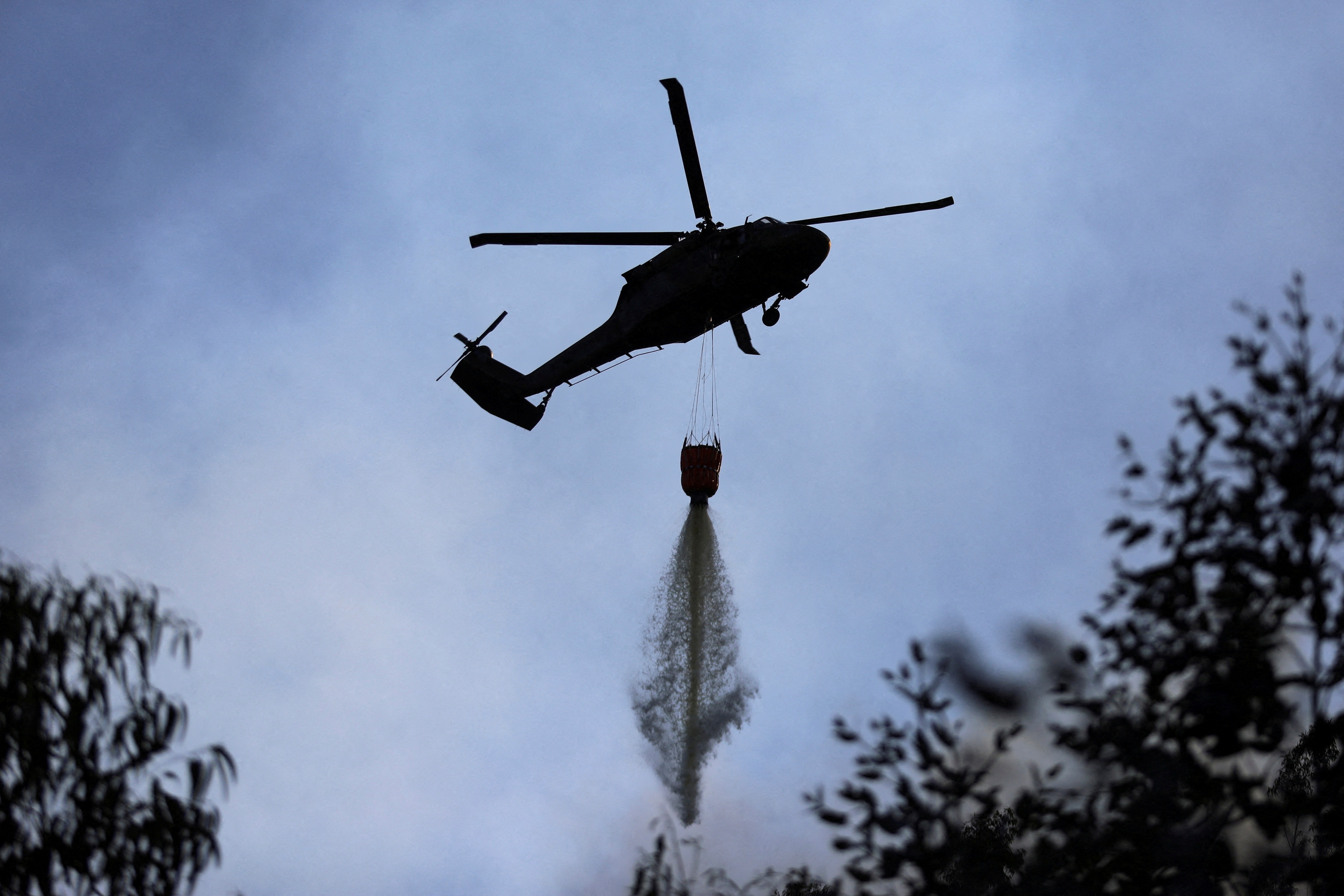 FILE PHOTO: A helicopter flies using water to put out forest fires in Nemocon, Colombia, January 25, 2024. REUTERS/Luisa Gonzalez/File Photo