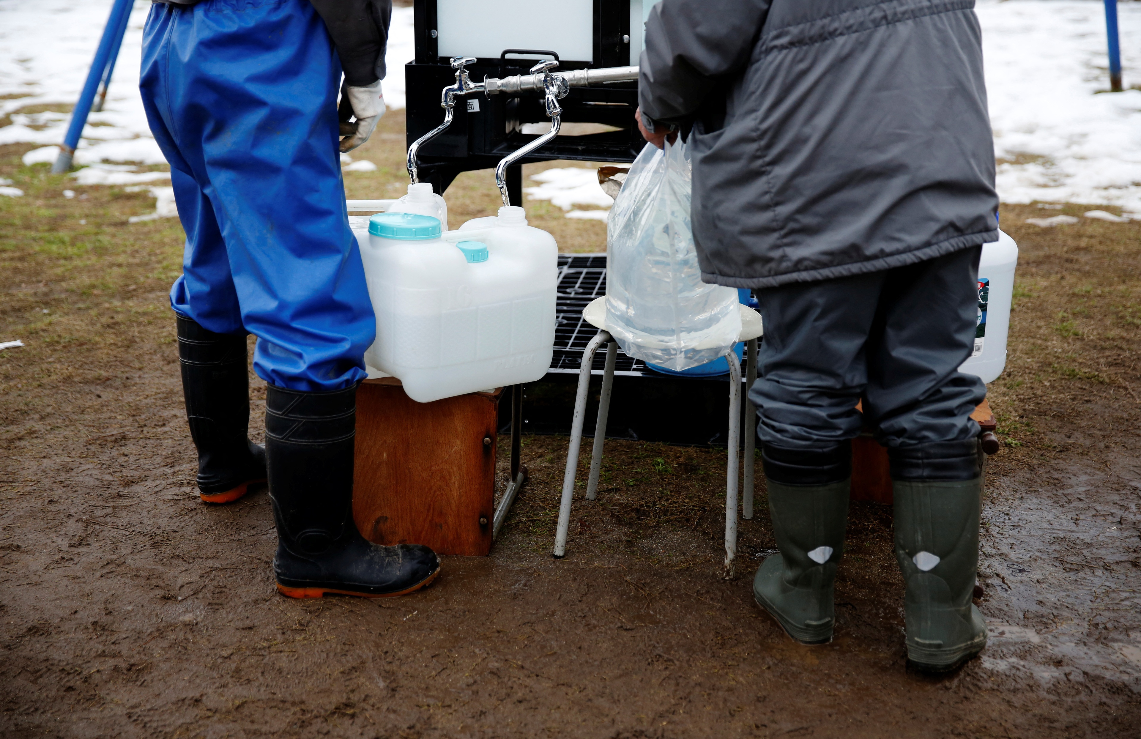 Locals fill up bottles from the communal water tank for Noto earthquake survivors in Suzu, Ishikawa Prefecture, Japan, January 30, 2024. REUTERS/Sakura Murakami